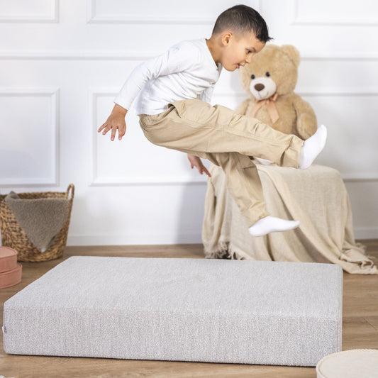 Kind springt fröhlich auf einem Hüpfpolster im Wohnzimmer – spielerische Bewegung für drinnen bei schlechtem Wetter