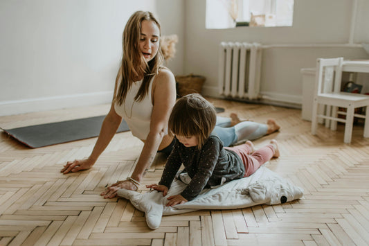 Mutter macht Yoga-Übungen mit ihrem Kind zuhause – spielerische Bewegung und Entspannung bei Regenwetter