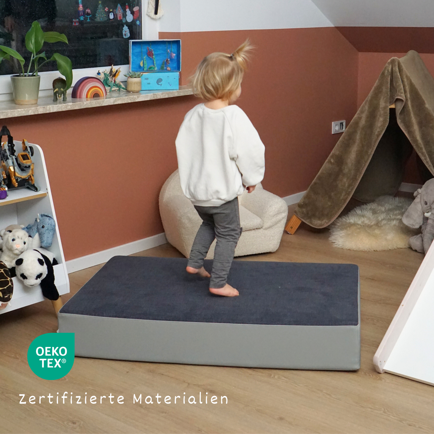 Kind spielt auf dem malwim Hüpfpolster Webstoff aus blau-grauem Webstoff im Kinderzimmer
