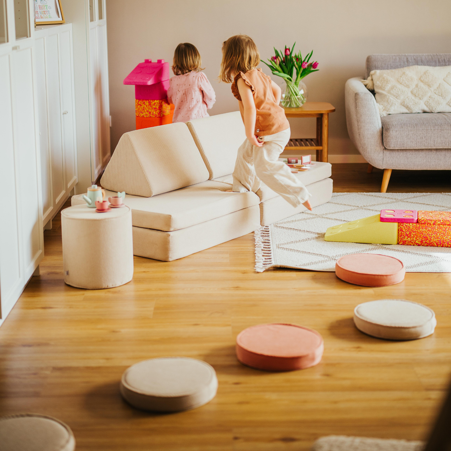 Kind spielt auf dem malwim Spielsofa Bundle S (Spielsofa + 4 Loopis) aus beigem, coralenem Cord im Kinderzimmer
